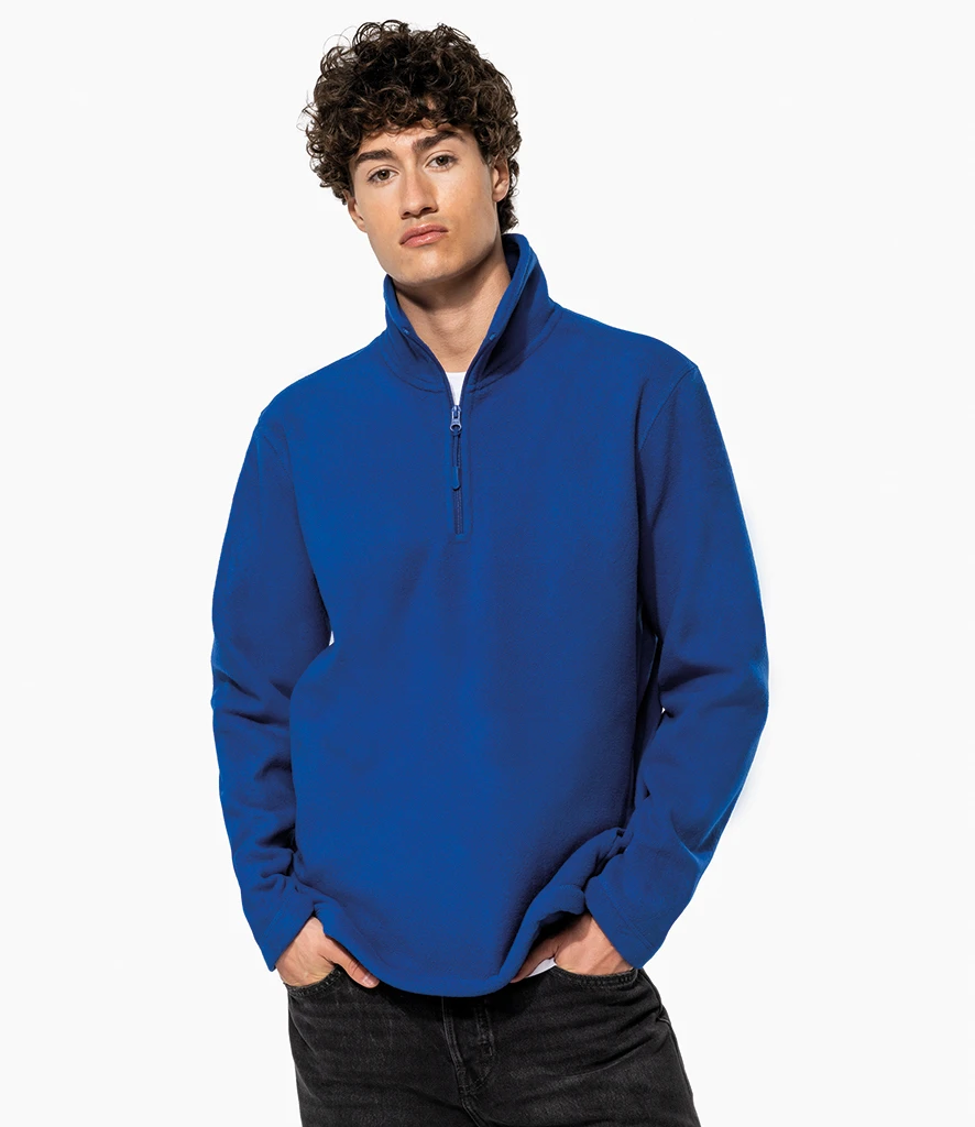 Man wearing a royal blue quarter-zip pullover with hands in pockets.