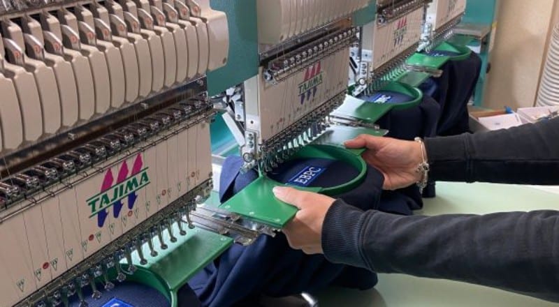 Industrial embroidery machines stitching branded workwear logos at SP Workwear production facility