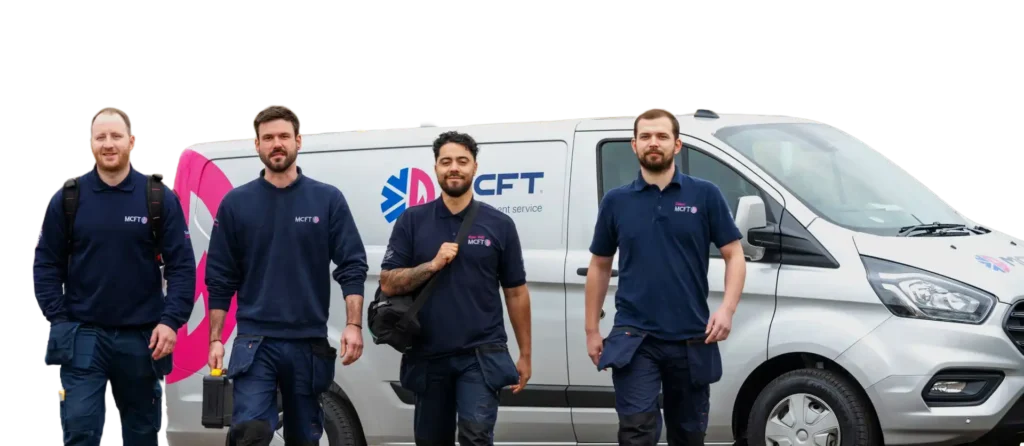 Four men in uniform standing in front of a van with the MCFT logo.