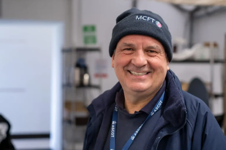 Man smiling and wearing MCFT branded beanie and workwear indoors.