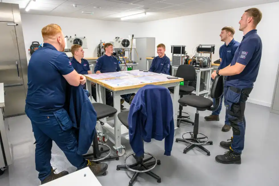 A team of engineers in matching branded polos and sweatshirts in their training room