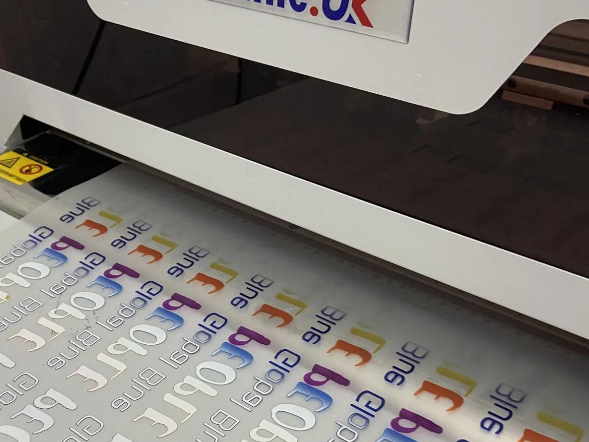 DTF transfer film with full-colour logos coming out of our DTF printer in Maidenhead