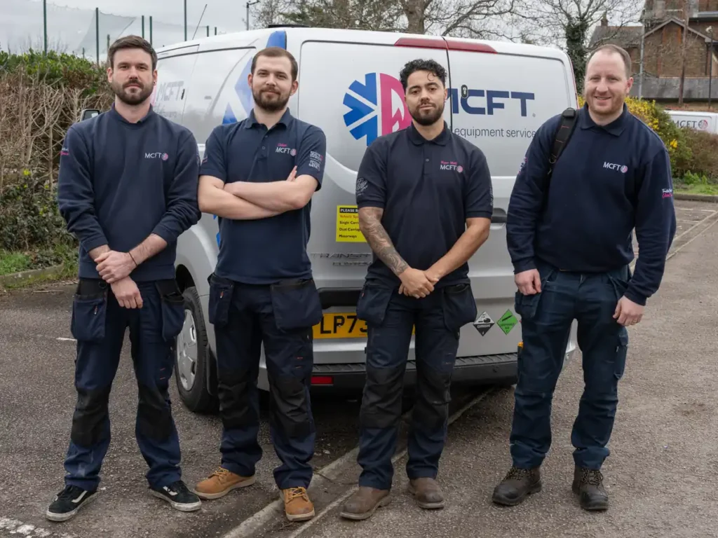 Engineers in branded navy polos and sweatshirts standing beside their company van